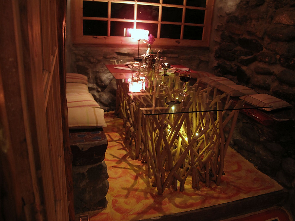 This dining table consists of a large piece of plate glass supported by a forest of tree branches.