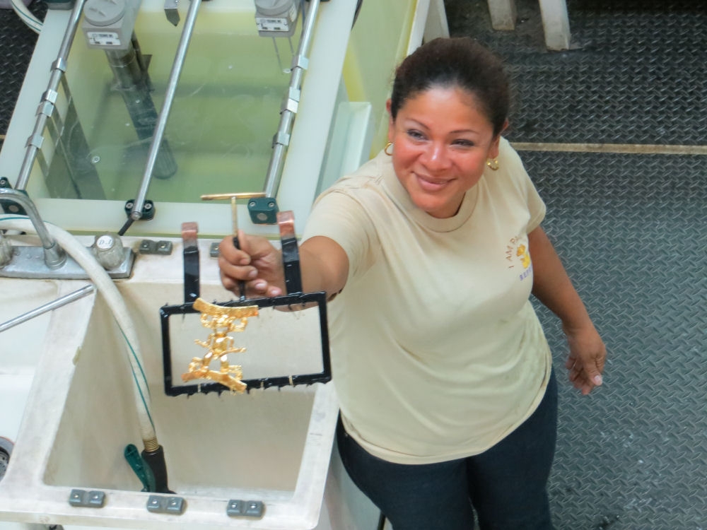 A worker shows off a gold-plated reproduction of a pre-Columbian artifact, fresh from the plating tanks at the Reposa Gold and Silver Factory.